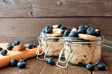 Wall Mural - overnight oats with fresh blueberries and bananas in a snap lid jar on a rustic wood background