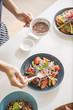© Lawren Lu/Stocksy - Female hands dressing fresh salad in kitchen background.
