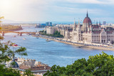 Fototapeta  - Travel and european tourism concept. Parliament and riverside in Budapest Hungary with sightseeing ships during summer day with blue sky and clouds