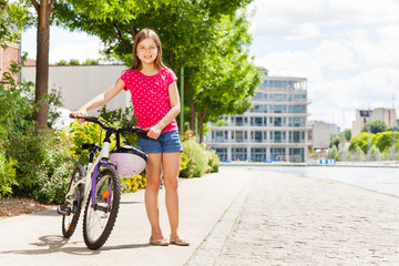 Wall Mural - Beautiful young girl with her bicycle at city park