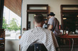 © Stocksy - Detail of back of mans head wearing barber gown and sitting in chair