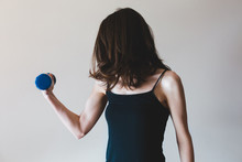 Thin Woman Flexing Her Muscle While Holding A Small Dumbbell
