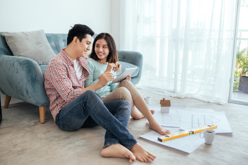 Attractive young asian adult couple looking at house plans.