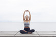 © Ulrika Kestere - Woman sitting in yoga lotus pose stretching her arms