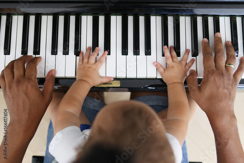 Plakat Maluch uczy się grać na pianinie z ojcem