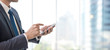 © bunditinay - Business man using smart phone on window with city building background and copy space.