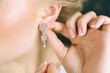 Elegant blonde bride putting on earrings, preparing for the wedding. Close-up