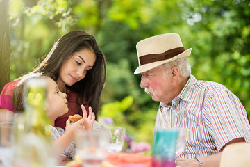 Poster - Three generations family picnic, grandfather plays with a kid