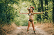 Beautiful little girl in image of nymph dryad stands in forest road and does spell.