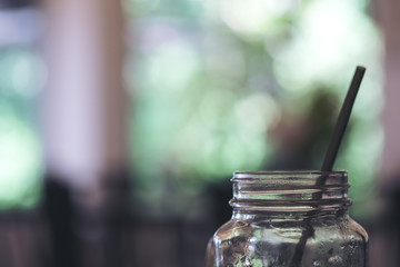 Wall Mural - Closeup image of a glass bottle and straw with blur green nature background