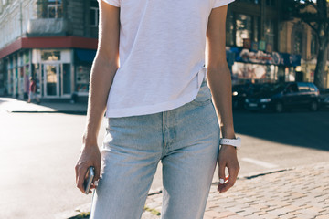 Slender girl in jeans and a white T-shirt on the background of the city