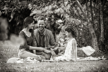 Wall Mural - Cheerful family sitting on the grass during un picnic in a park