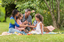 Cheerful Family Sitting On The Grass During Un Picnic In A Park