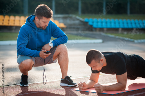 Fotografía morning plank exercises with personal coach with stopwatch;