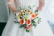 Beautiful bridal bouquet with white roses and peach peonies in a bride hands in white dress. Wedding morning. Close-up