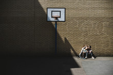 Young Couple Sitting In A Basketball Court