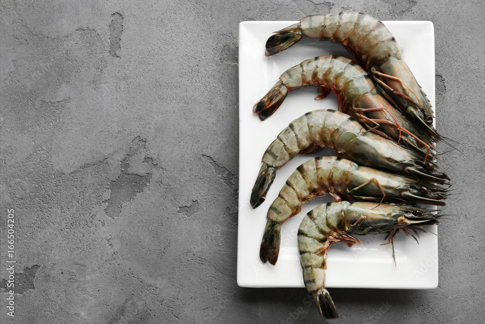 Plate with fresh shrimps on grey background