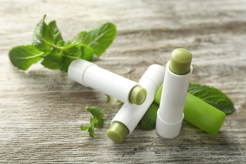 Wall Mural - Hygienic lipsticks with lemon balm on wooden background