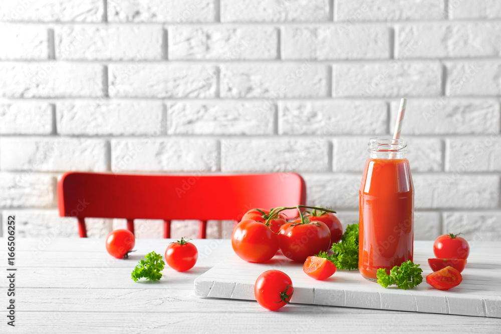 Delicious juice in bottle and tomatoes on wooden board