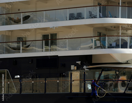 A Passenger Lies In A Hammock As A Crewman Carries Out