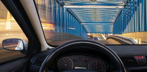 Wall Mural - A view of the cockpit of a car driving at night through an illuminated bridge.