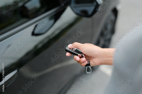 Fotografie, Obraz woman hand using interlock remote to open door of a car.