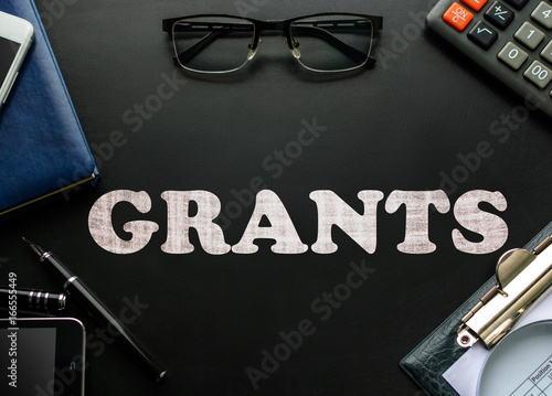 Fotografía Text Grants on a black chalkboard with business accessories (notebook, tablet, mobile phone, glasses, fountain pen)