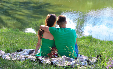 Two lovers sit on the shore of the lake