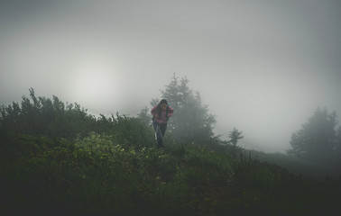 Wall Mural - hiker in dense fog on a rugged terrain trail