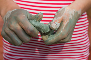 Child models handicraft in lump of clay by hands