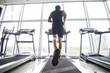 © F8  \ Suport Ukraine - Back view of young man athlete with running on treadmill in gym. Fitness gym.