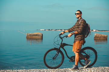 Poster - Young Male Cyclist With Bicycle Walking On Coast And Enjoying View Of Sea. Holiday Travel Activity Concept