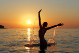 Fototapeta  - Sylwetka kobiety w wodzie na tle zachodzącego słońca