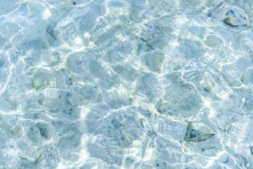 Abstract water wave, sun reflections in pool water with stone background.