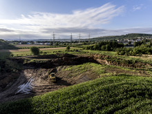 Top View Heavy Machine Excavator Bagger Working In Mud On Construction Site With Green Landscape Surrounding