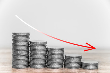 Red downward arrow with coins stacks background, Economic graphs with the curve down.