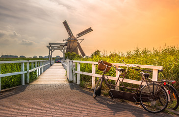 Traditional village with dutch windmills and river at sunset, Holland, Netherlands.