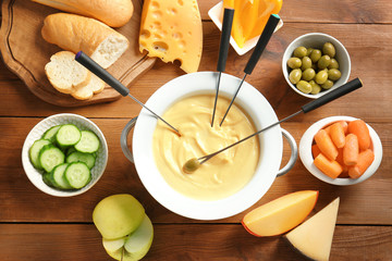 Wall Mural - Cheese fondue in pot and different products on wooden table