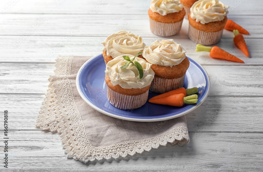 Plate with delicious carrot muffins on wooden table