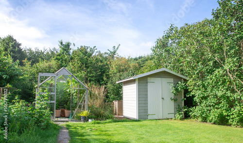 Fotomural Greenhouse and shed in green lush garden