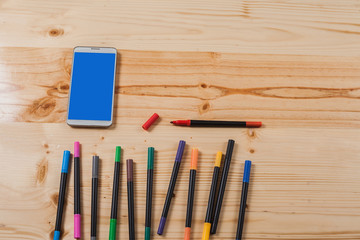 color pen and mobile phone on wood table .