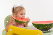 A child, a little girl, appetizingly eats a juicy watermelon.