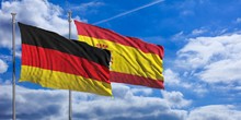 Spain And  Germany Waving Flags On Blue Sky. 3d Illustration