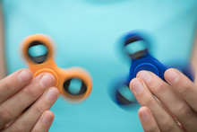 A Young Girl Holding And Twisting Two Spinners Of Blue And Orange In The Summer