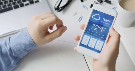 Checking wather using smartphone app. Rainy and cloudy weather