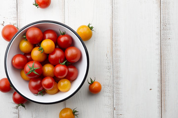 Wall Mural - Bright red and yellow tomatoes on white wooden table, top view