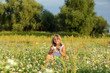 Śliczna uśmiechnięta dziewczynka bawi się kwiatami na łące.
