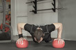 © lenblr - Sportsman wearing black shorts and t-shirt doing push-ups exercise on the ball in gym.
