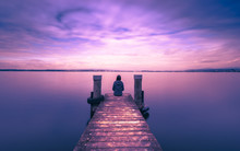 Mystical World. A Lone Figure On The Pier Of The Lake. Long Exposure.