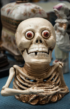 Funny greedy skeleton figurine at flea market in Paris (France). Death concept.